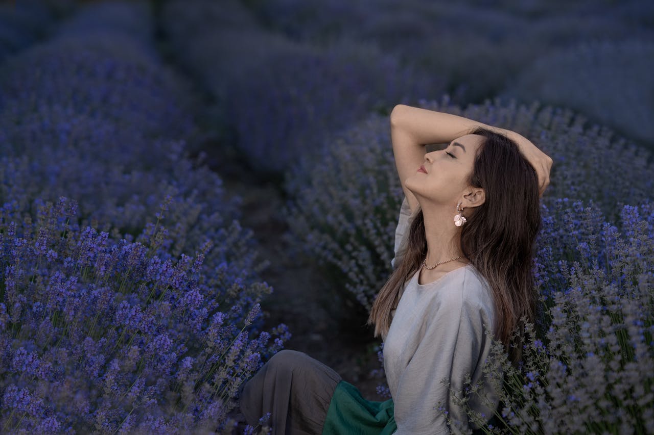 Serene woman enjoying tranquility in a blooming lavender field under twilight.
